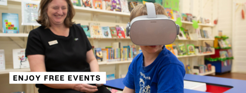 A boy wearing a virtual reality headset and a library officer laughing
